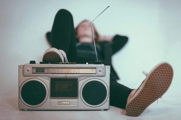A young music enthusiast reclines with head on his hands and a boom box at his feet.